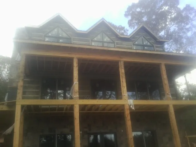 Dormers and porch framing on a large log home under construction — Roof Coating work by our crew in White