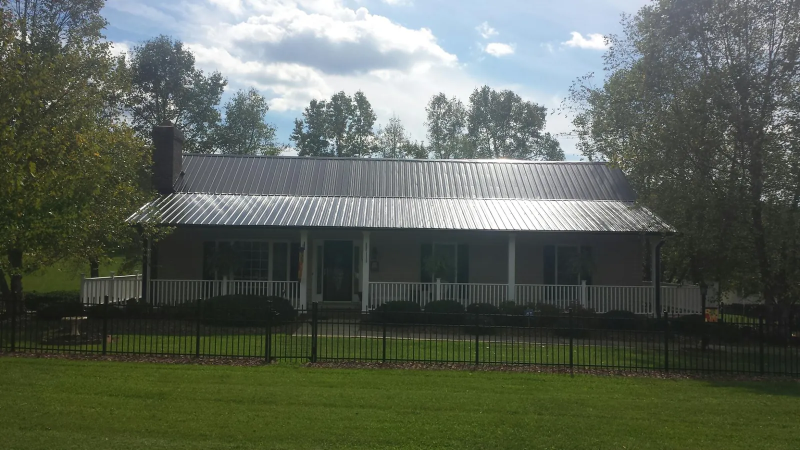 Gray metal roof on a brick ranch with a full width front porch — Gutter Guard Installation work by our crew in White