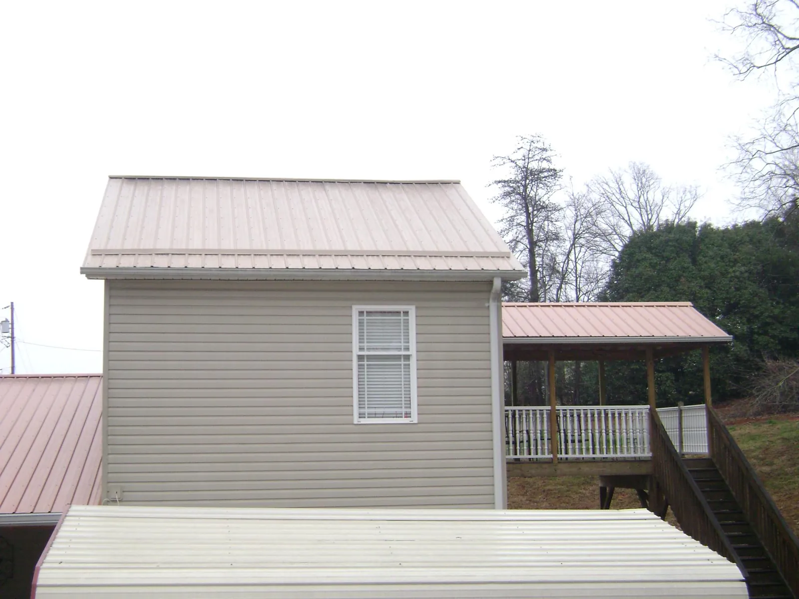 Tan metal roofs on a two story addition and attached porch, from a Roof Replacement job in White